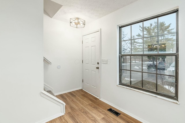 entryway with a textured ceiling and light wood-type flooring