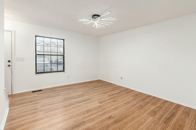 unfurnished room with a textured ceiling and light hardwood / wood-style flooring