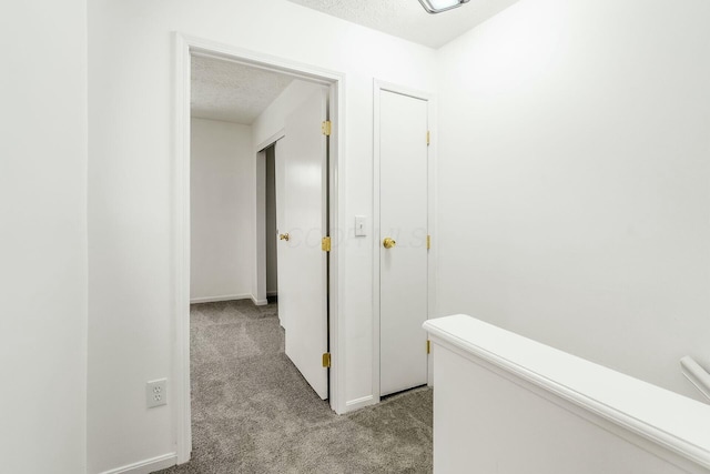 corridor with light carpet and a textured ceiling