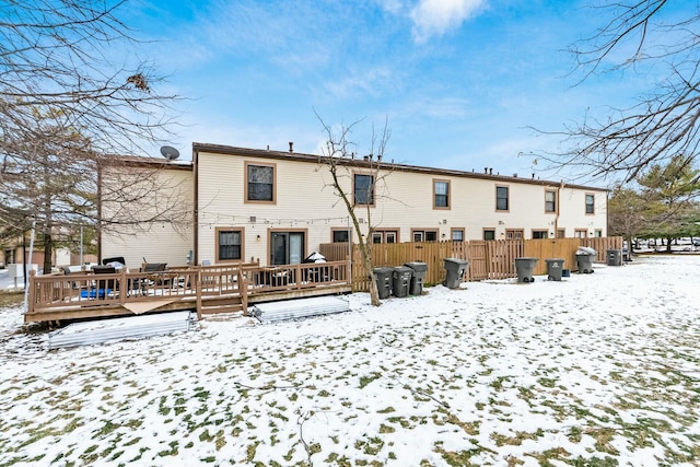 snow covered back of property featuring a wooden deck