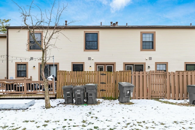 snow covered rear of property with a deck