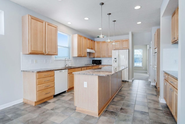 kitchen featuring pendant lighting, white appliances, a kitchen island, and light brown cabinets