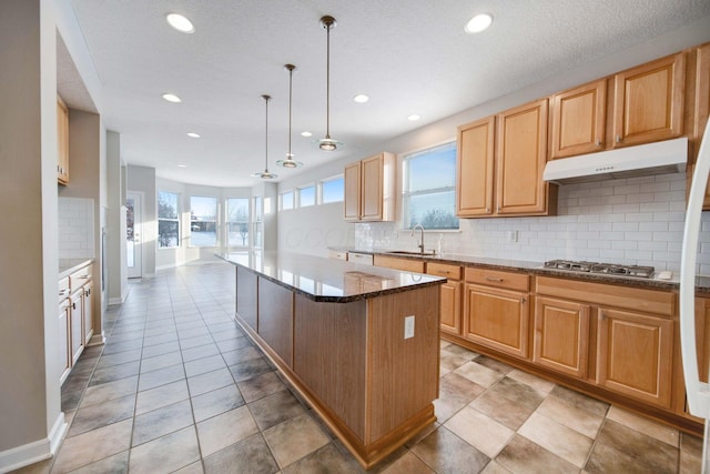 kitchen with a healthy amount of sunlight, decorative light fixtures, a center island, and stainless steel gas stovetop