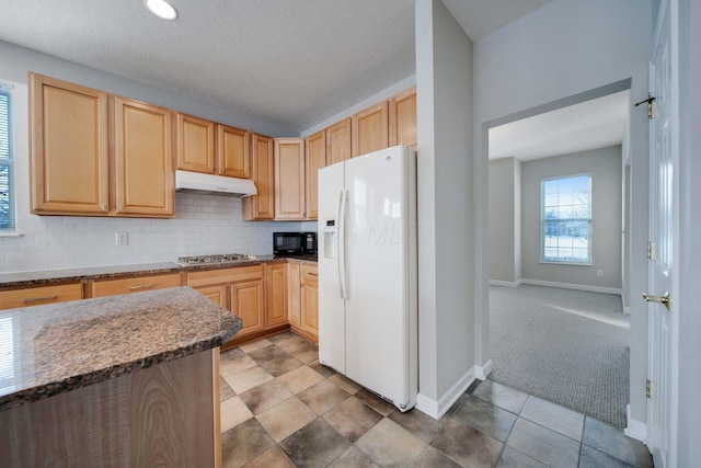 kitchen with stainless steel gas cooktop, light brown cabinets, carpet flooring, white fridge with ice dispenser, and dark stone counters