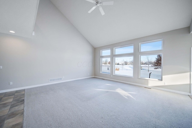 carpeted empty room with ceiling fan, plenty of natural light, and high vaulted ceiling