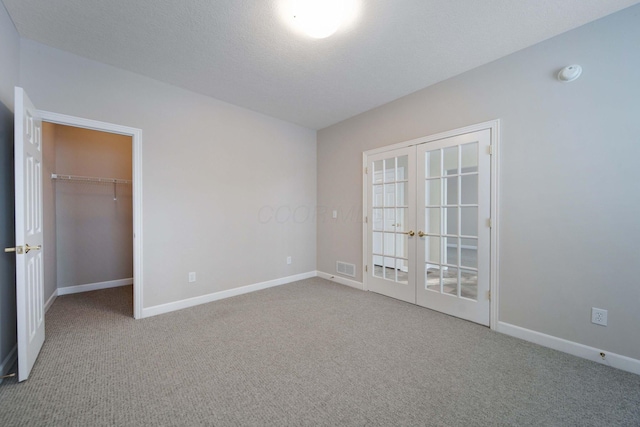 carpeted empty room with a textured ceiling and french doors