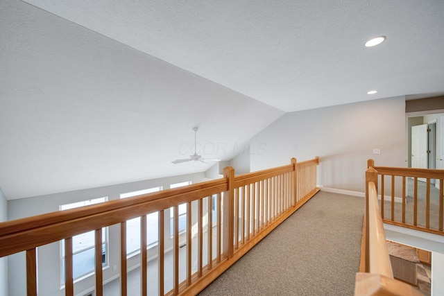 corridor with lofted ceiling, carpet floors, and a textured ceiling