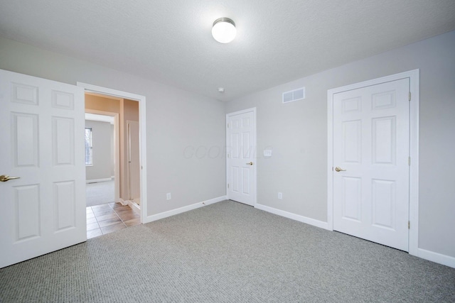 unfurnished bedroom with light colored carpet and a textured ceiling