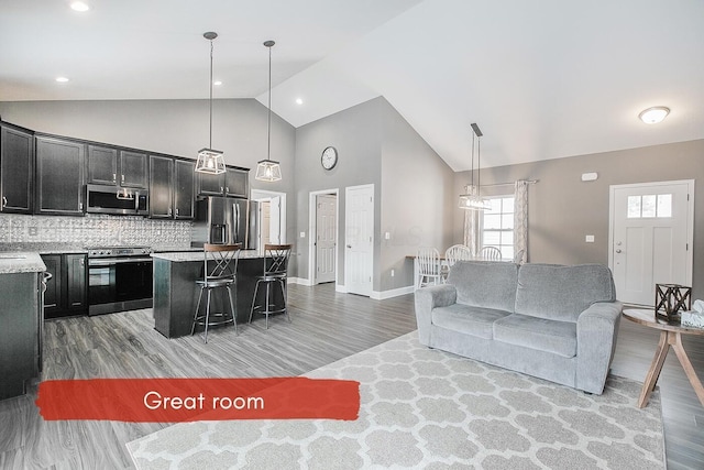 living room featuring wood-type flooring, sink, and high vaulted ceiling