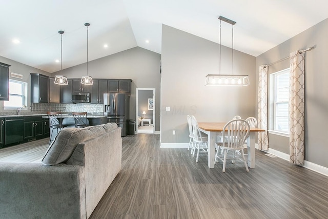 kitchen with hanging light fixtures, a kitchen island, appliances with stainless steel finishes, and dark wood-type flooring