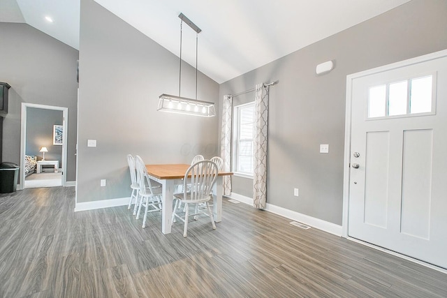 dining area with wood-type flooring and high vaulted ceiling