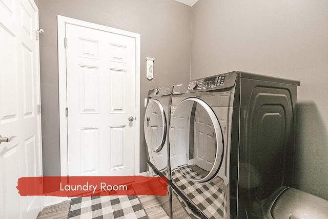 laundry area with hardwood / wood-style flooring and washing machine and clothes dryer