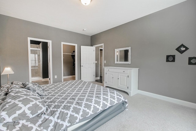 bedroom with ensuite bathroom, a spacious closet, light carpet, and a closet