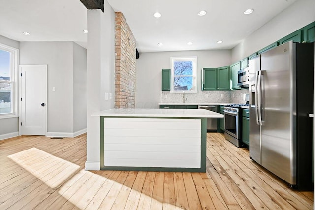 kitchen with green cabinetry, appliances with stainless steel finishes, backsplash, and kitchen peninsula