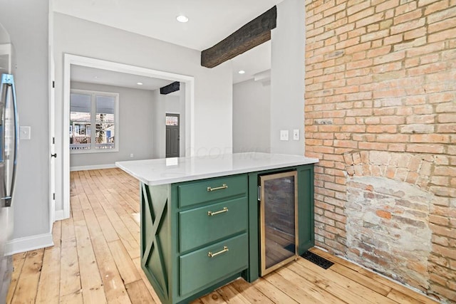 kitchen with light hardwood / wood-style flooring, beverage cooler, beam ceiling, and green cabinetry