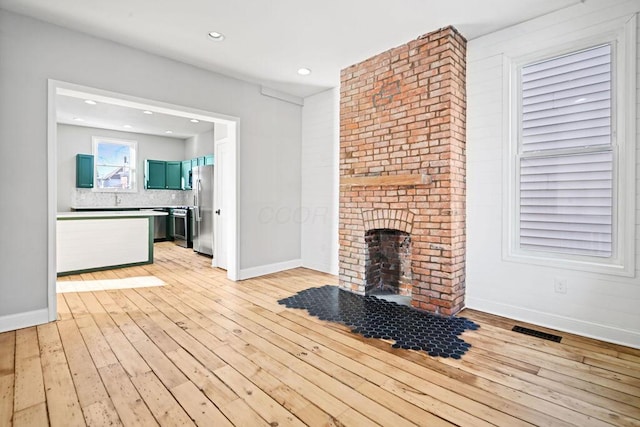 unfurnished living room with light hardwood / wood-style floors and a brick fireplace