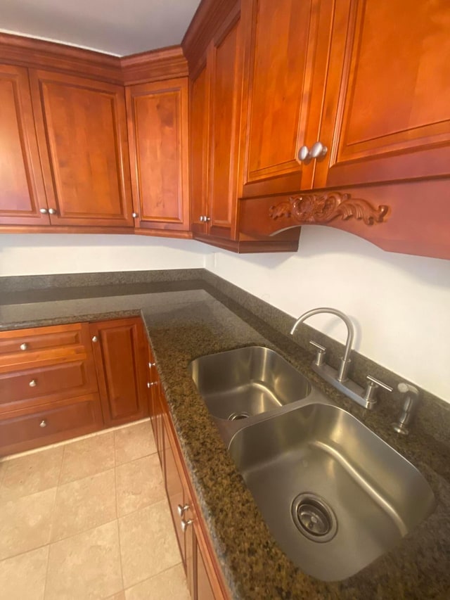 kitchen with dark stone countertops, sink, and light tile patterned flooring