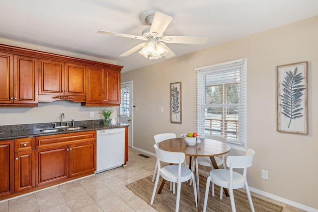 kitchen with light tile patterned flooring, dishwasher, sink, dark stone countertops, and ceiling fan