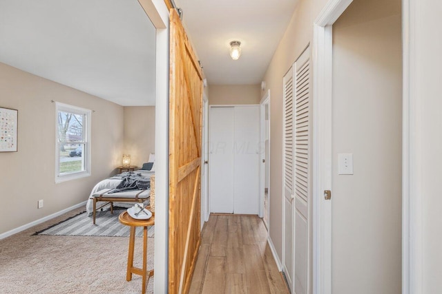 hall featuring a barn door and light hardwood / wood-style flooring