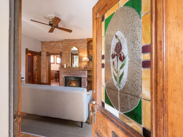 living room with ceiling fan, brick wall, and a fireplace