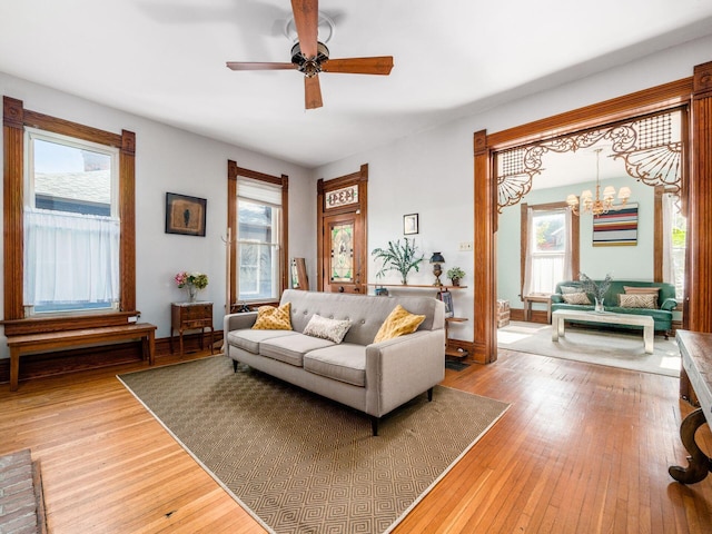 living room with hardwood / wood-style flooring, plenty of natural light, and ceiling fan with notable chandelier