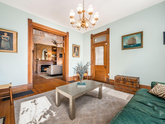 living room with a brick fireplace, hardwood / wood-style floors, and an inviting chandelier