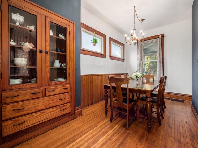 dining area featuring hardwood / wood-style flooring, a notable chandelier, and wooden walls