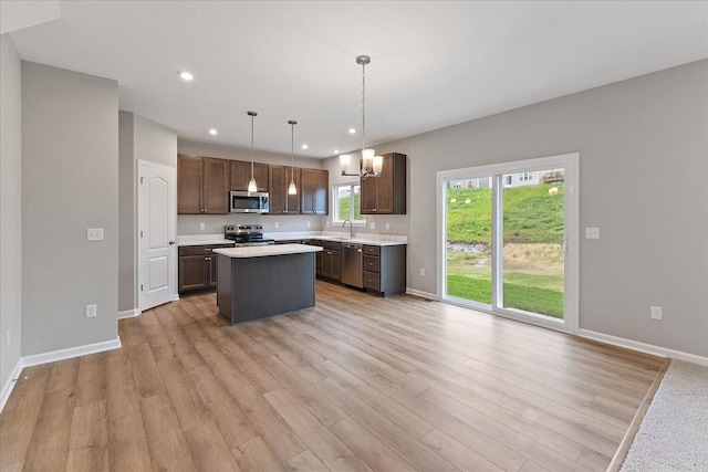 1208 Heathgate Way, Fairborn, OH 45324 - kitchen featuring stainless steel appliances, a sink, light countertops, a kitchen island, and light wood-style flooring