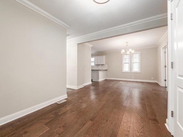 unfurnished living room featuring crown molding, dark wood-type flooring, and an inviting chandelier