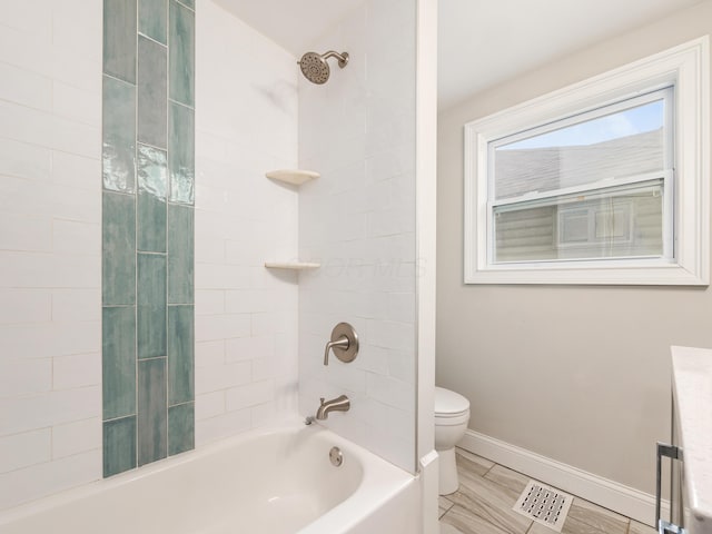 bathroom featuring tiled shower / bath and toilet