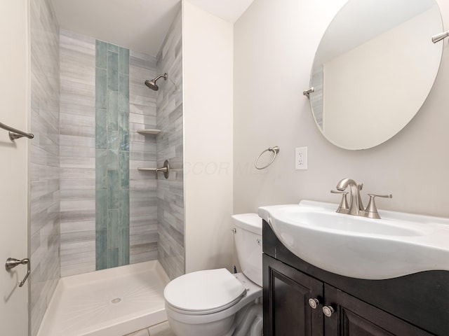 bathroom featuring vanity, toilet, and tiled shower