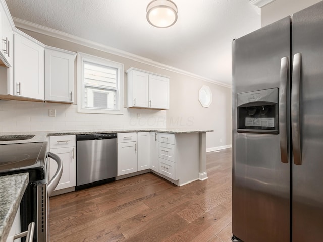 kitchen with light stone countertops, appliances with stainless steel finishes, white cabinets, and backsplash