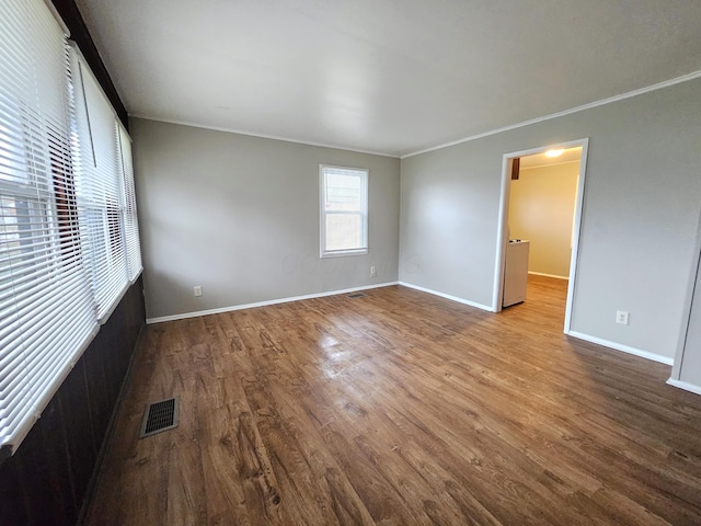 empty room with hardwood / wood-style floors and crown molding