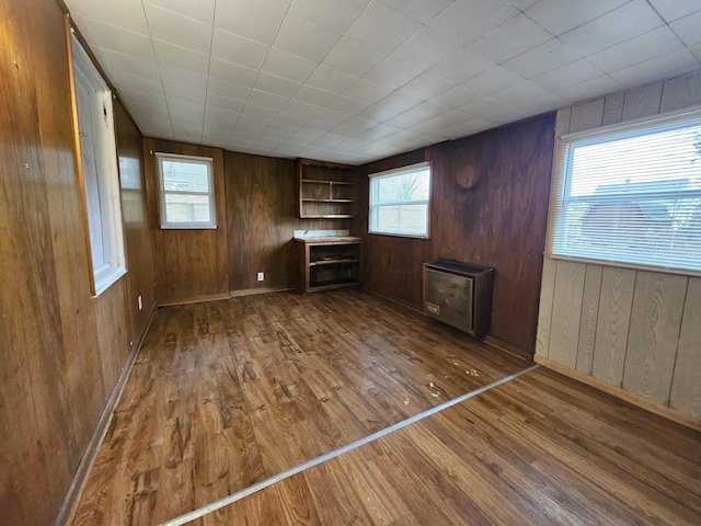 unfurnished living room featuring hardwood / wood-style flooring, plenty of natural light, and wooden walls