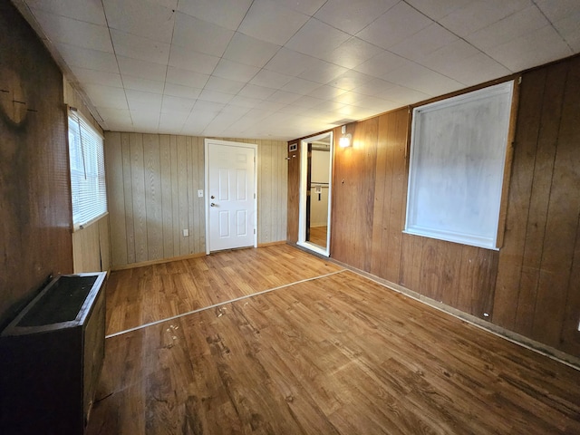 unfurnished bedroom with hardwood / wood-style floors and wood walls