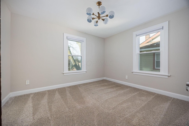 spare room with a chandelier and carpet floors