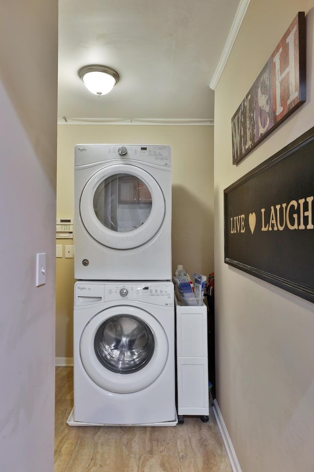 washroom featuring stacked washer and dryer and ornamental molding