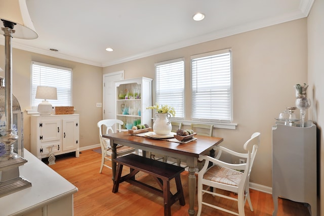 dining space featuring ornamental molding and light hardwood / wood-style floors