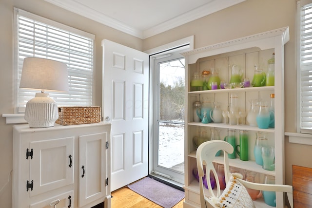 doorway featuring crown molding and light hardwood / wood-style floors