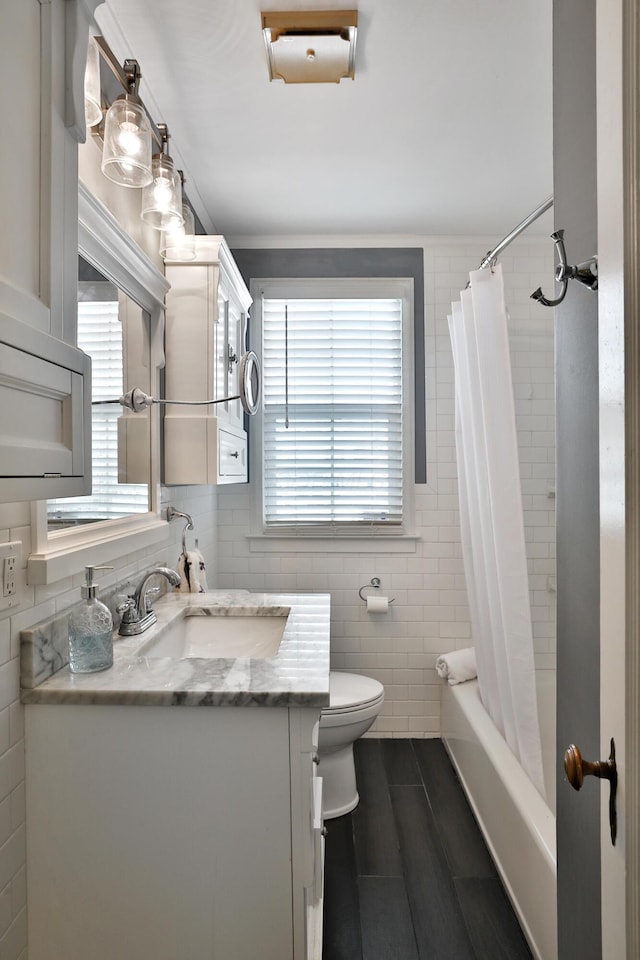 full bathroom with tile walls, vanity, a wealth of natural light, and toilet