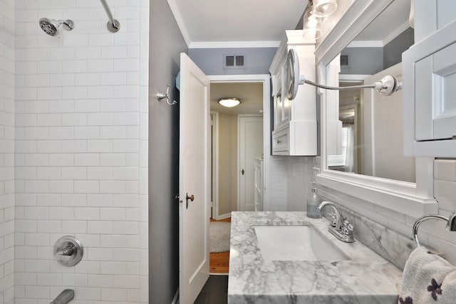 bathroom with tiled shower / bath combo, ornamental molding, and vanity