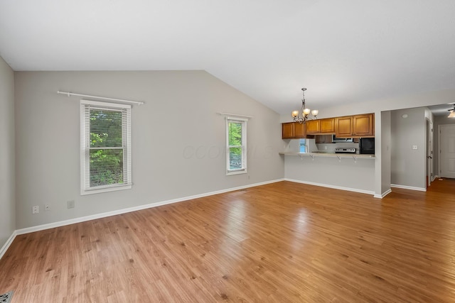 unfurnished living room with a chandelier, vaulted ceiling, and light wood-type flooring