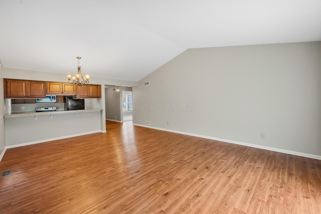 unfurnished living room with lofted ceiling, a chandelier, and light hardwood / wood-style floors