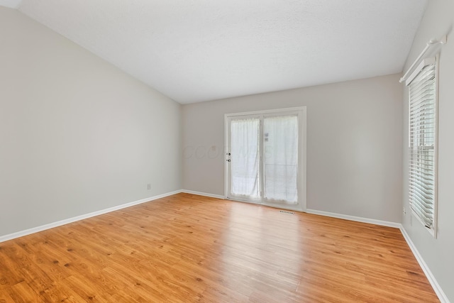 spare room featuring lofted ceiling and light wood-type flooring