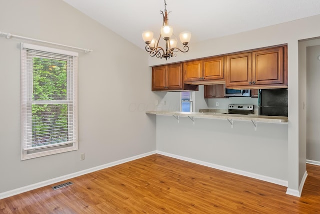 kitchen with lofted ceiling, a kitchen breakfast bar, kitchen peninsula, pendant lighting, and stainless steel appliances