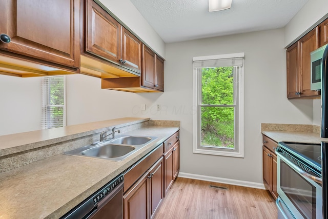 kitchen with sink, light hardwood / wood-style flooring, a textured ceiling, appliances with stainless steel finishes, and kitchen peninsula