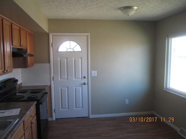 kitchen featuring black range with electric stovetop, a healthy amount of sunlight, dark wood-type flooring, and a textured ceiling