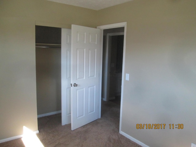 unfurnished bedroom featuring light carpet and a closet