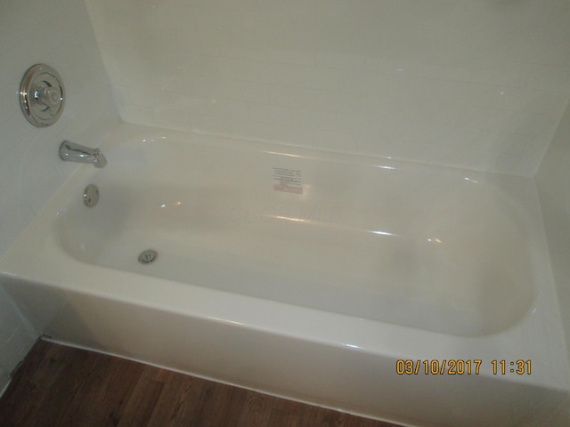 bathroom with hardwood / wood-style flooring and a bath