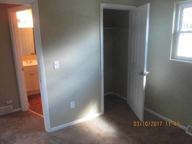 unfurnished bedroom featuring ensuite bathroom, a spacious closet, carpet flooring, and a closet